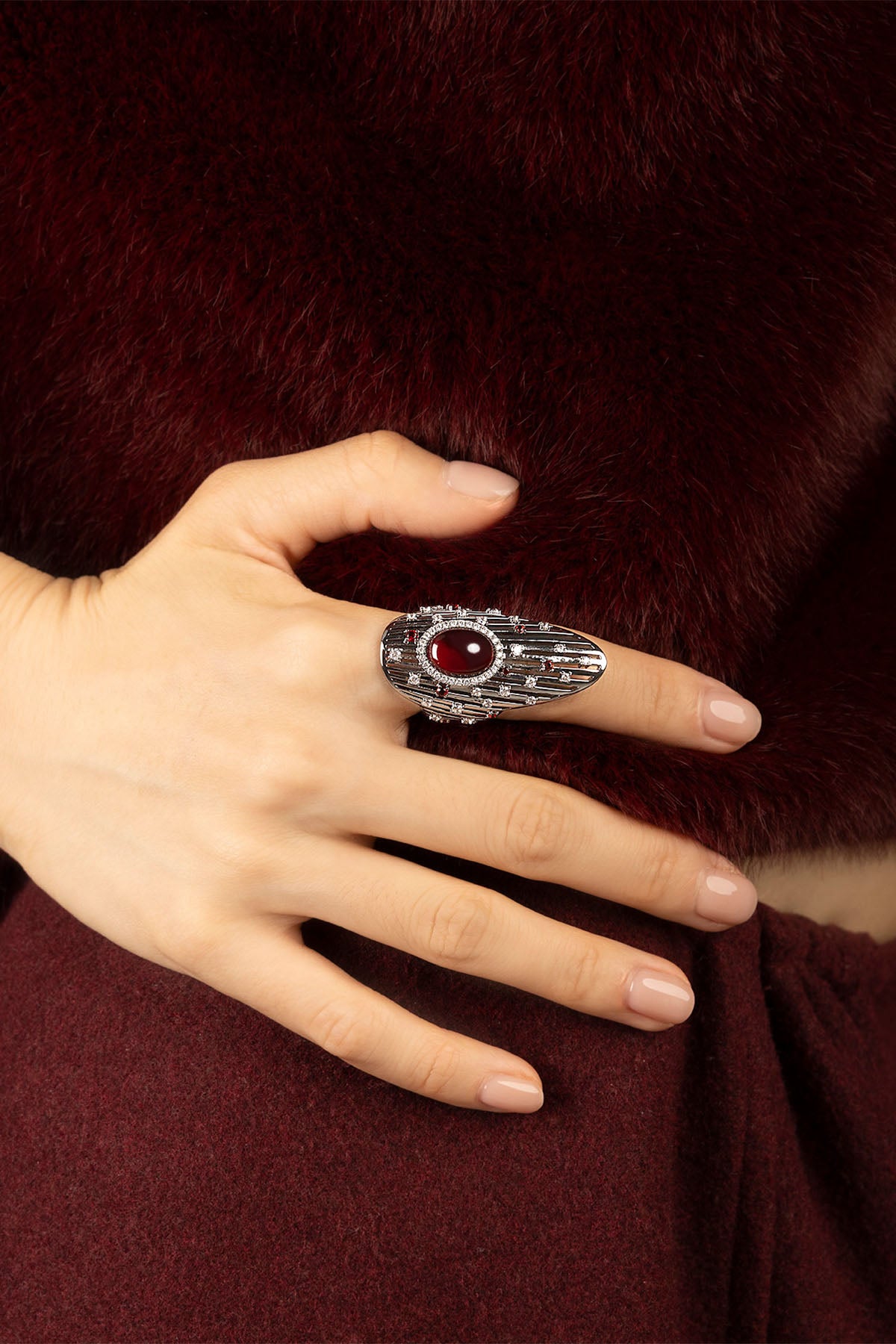 Woman wearing APM Monaco ring, a bold red gem glowing against rhodium finish.