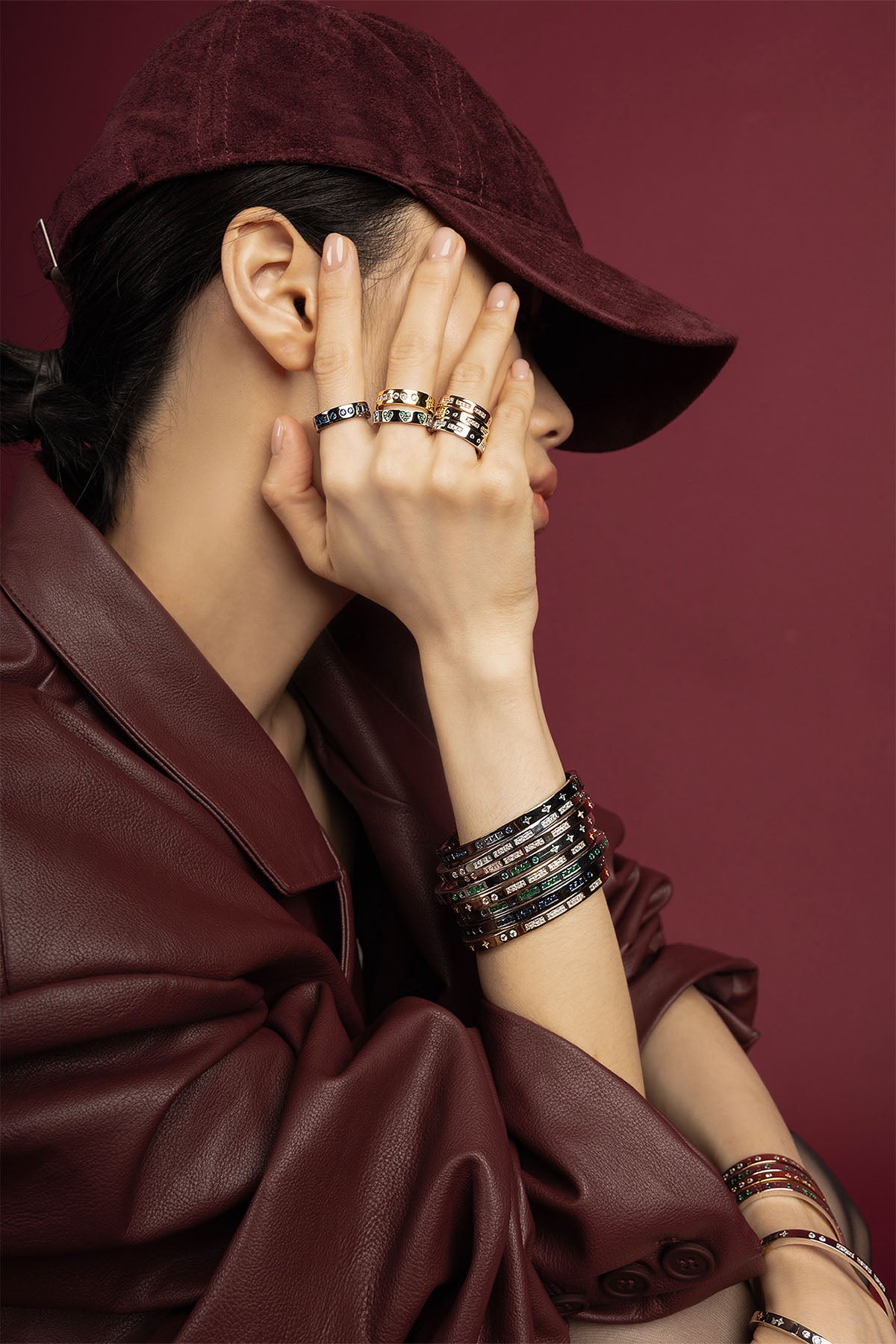 Woman wearing stacked APM Morse Rings and Bracelets, a bold burgundy statement.