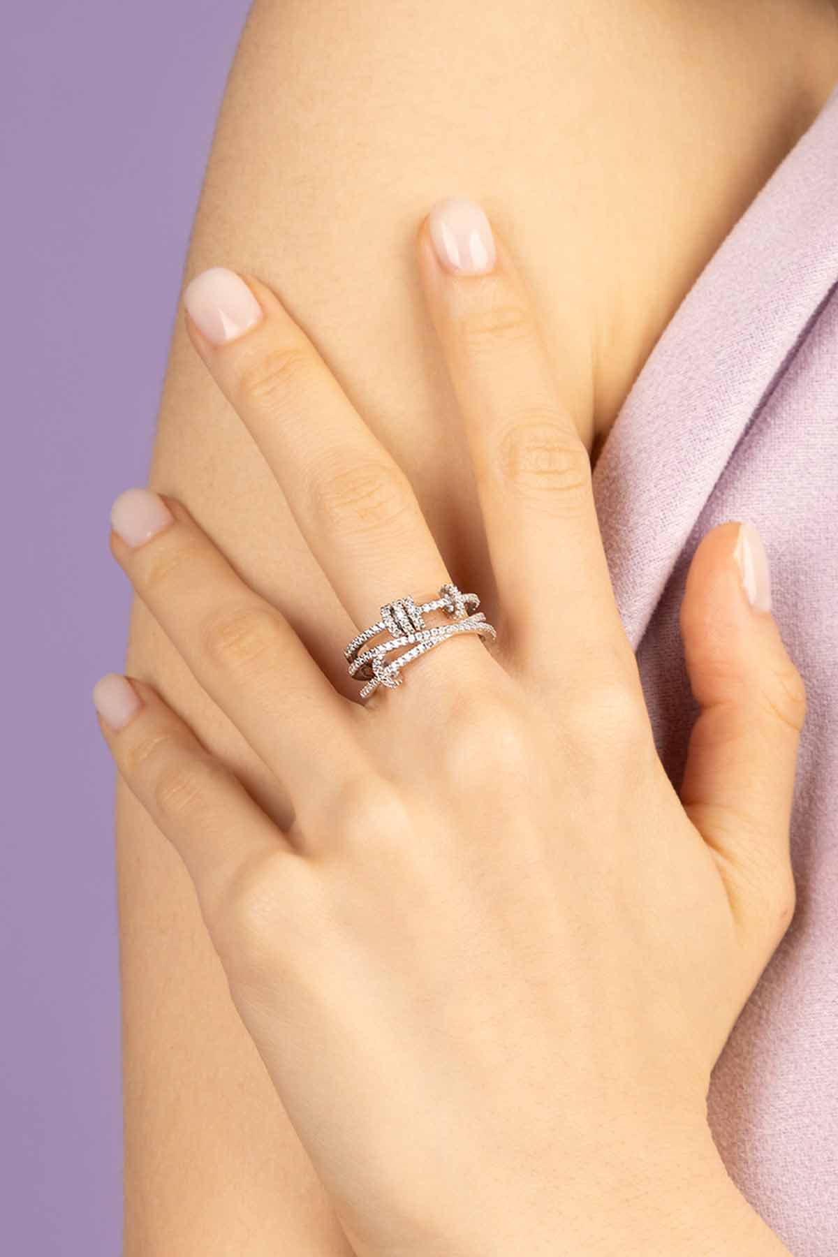 Hand wearing APM MONACO triple ring with sliding hoops ring in silver with a purple background