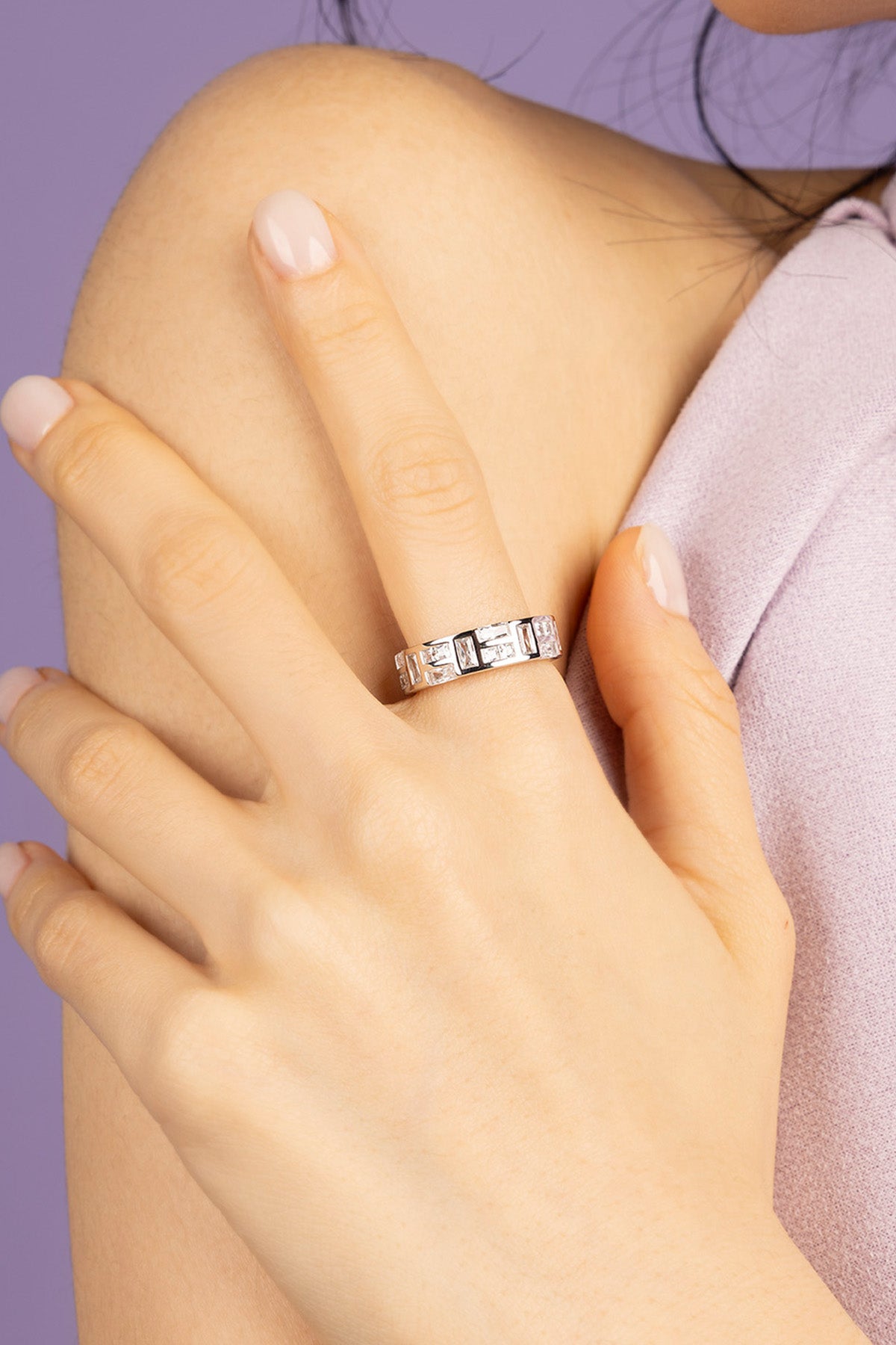 Hand wearing APM MONACO ice Silver-tone ring on a purple background