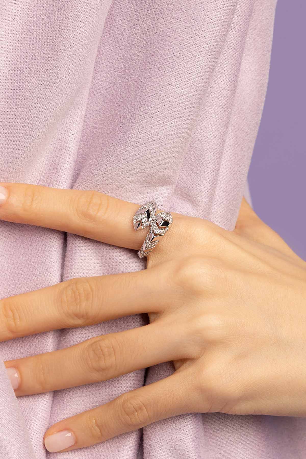 Close-up of a hand wearing a Silver-tone ring with a zirconia on a light purple fabric background