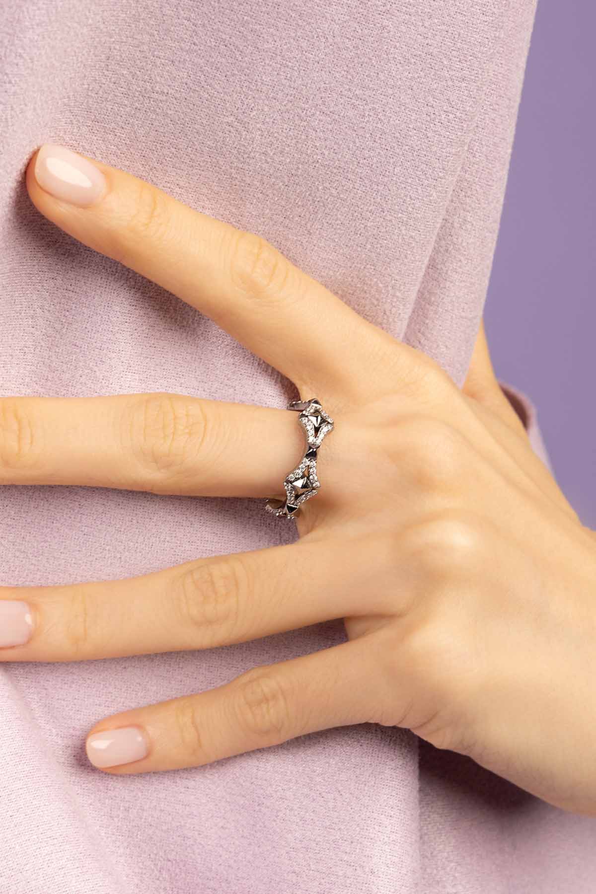 Hand wearing a silver ring with a zirconia on a light purple background