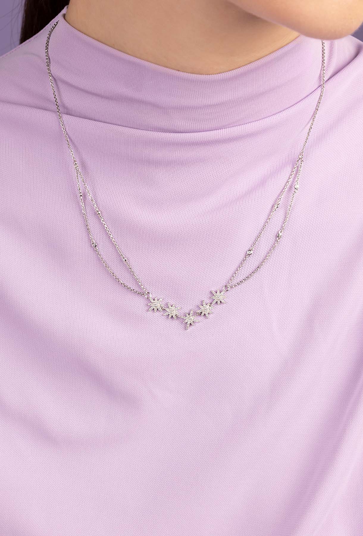 Necklace with floral pendants on a person wearing a light purple top