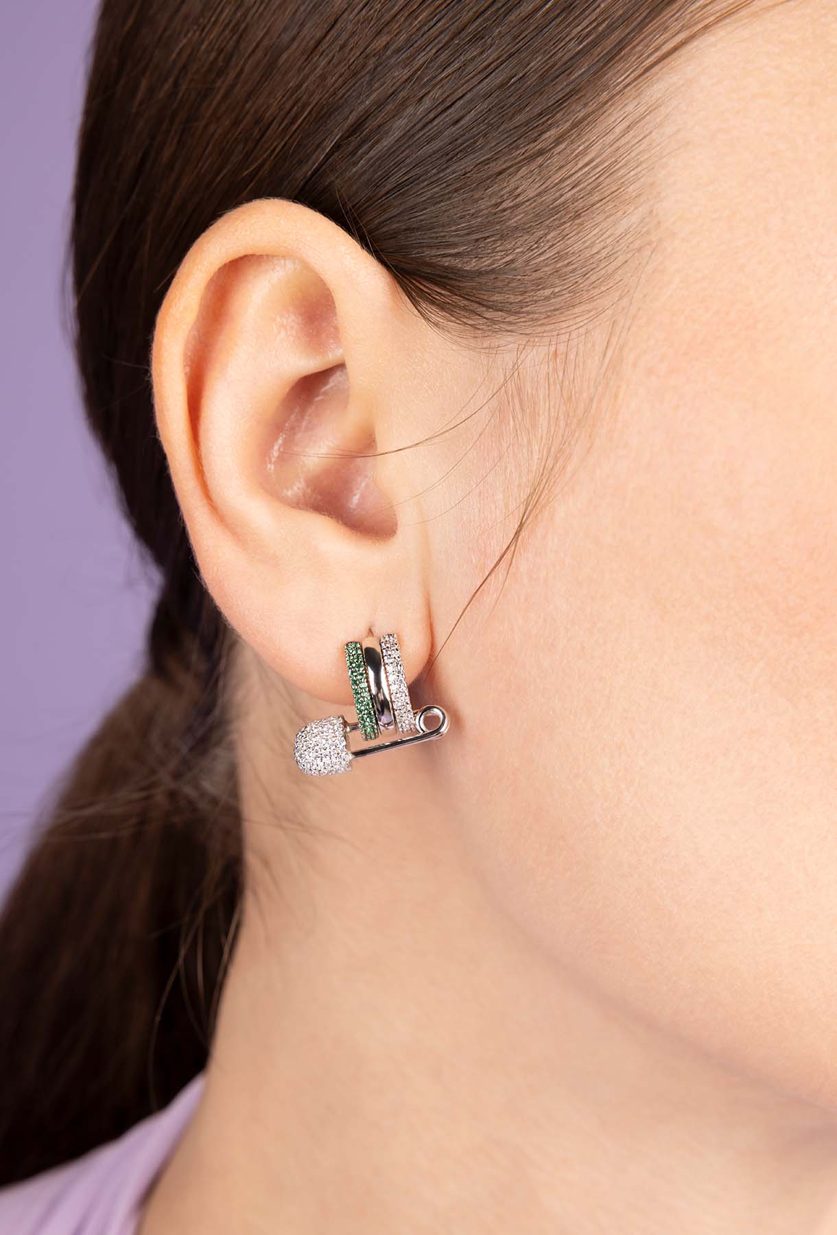 Close-up of an ear wearing a unique earring with a purple background