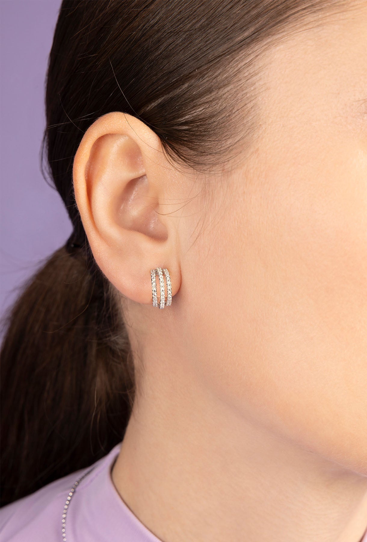 Close-up of an ear wearing APM MOANCO silver hoop earring with a blurred background