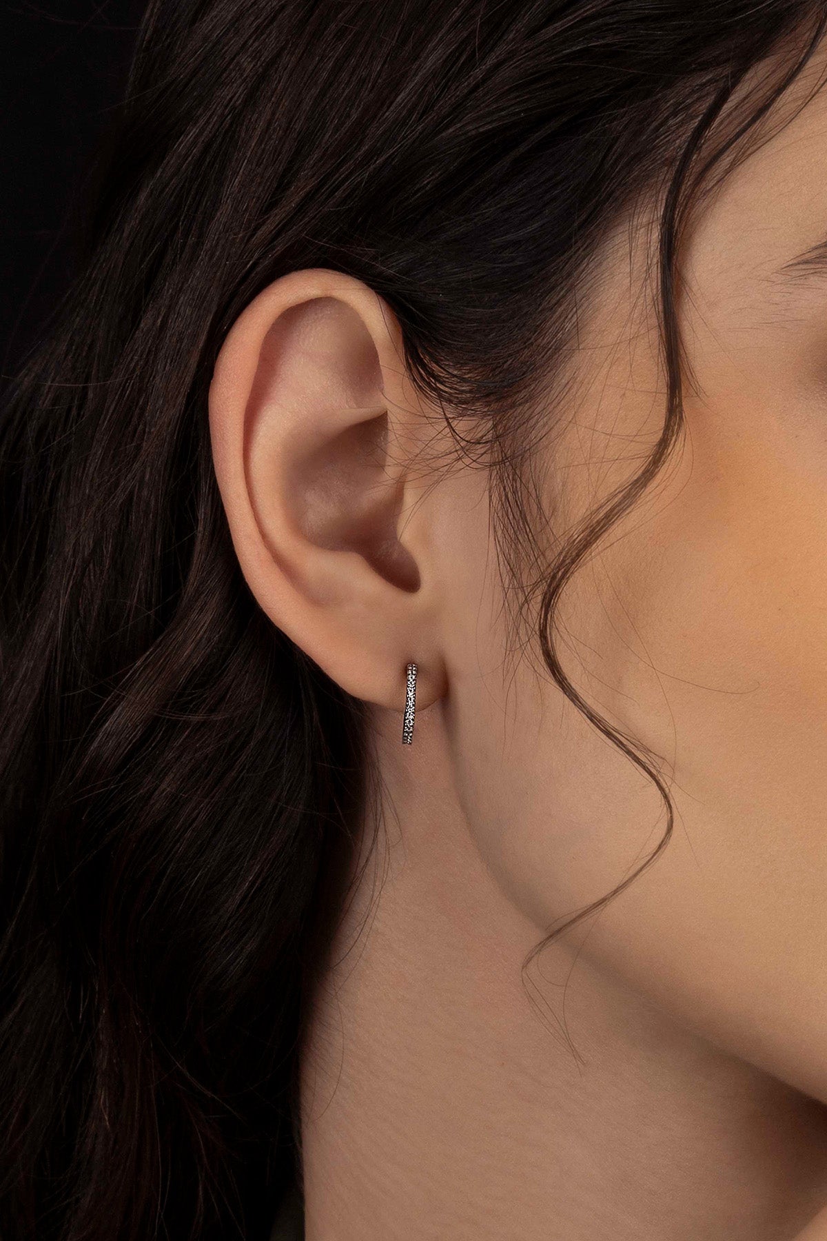 Close-up of an ear wearing a silver hoop earring