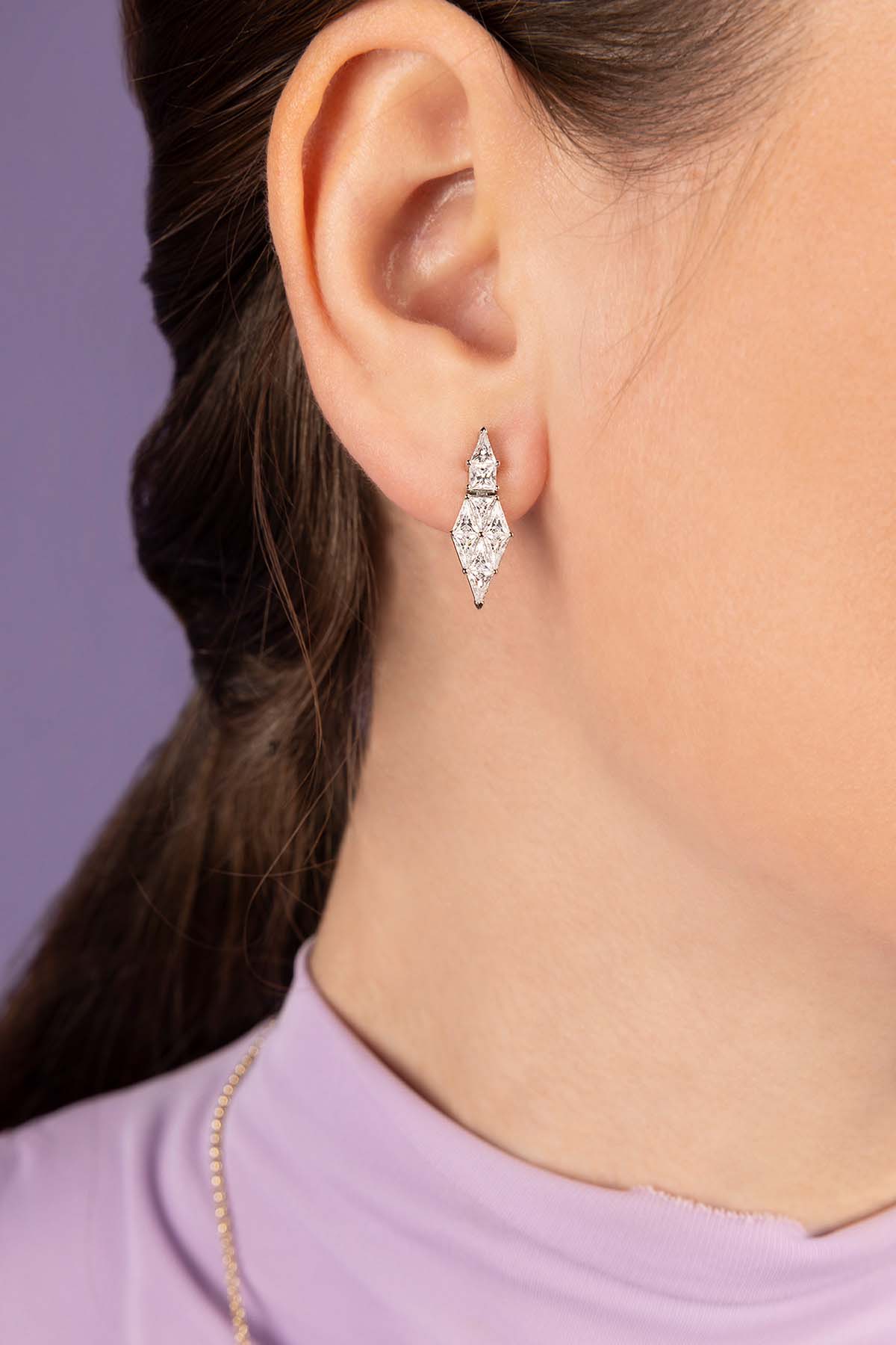 Close-up of a zirconia earring worn by a person with a purple background