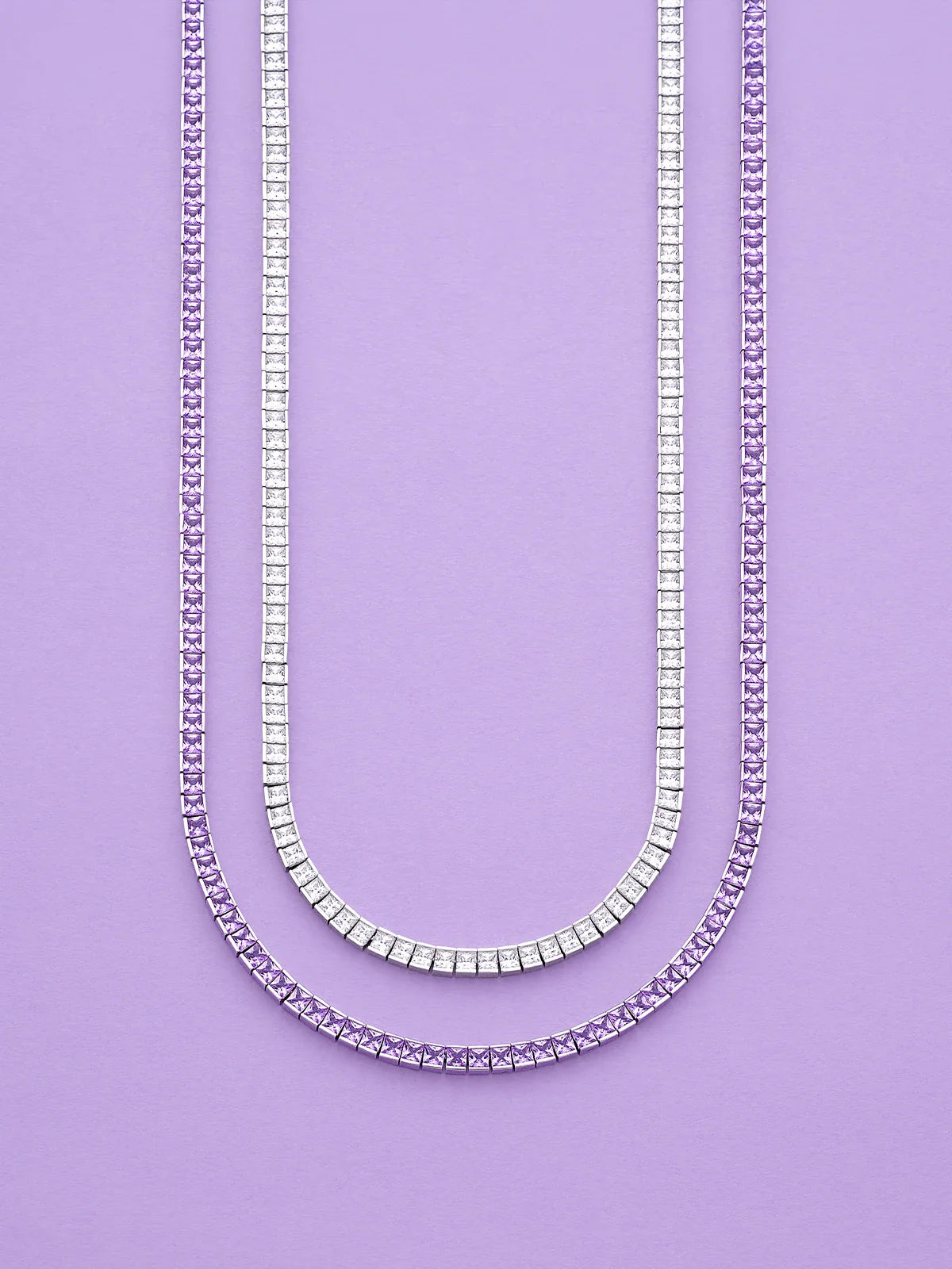 Two APM MONACO Printemps necklaces in silver and purple on a purple background
