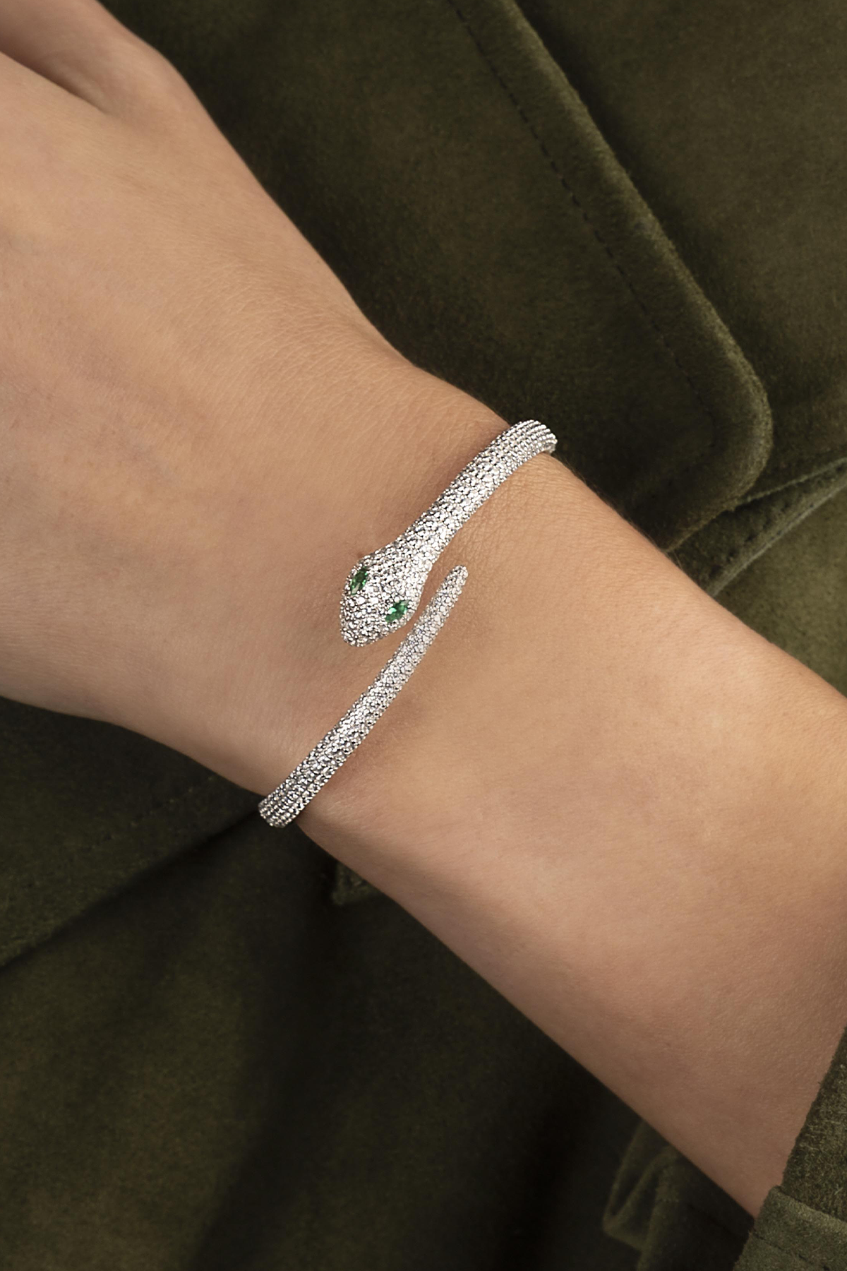 APM MONACO KAA Wrap Cuff in silver on a wrist against a green background