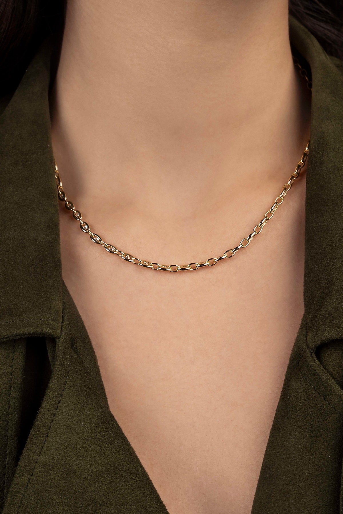 Gold chain necklace on a person wearing a green shirt
