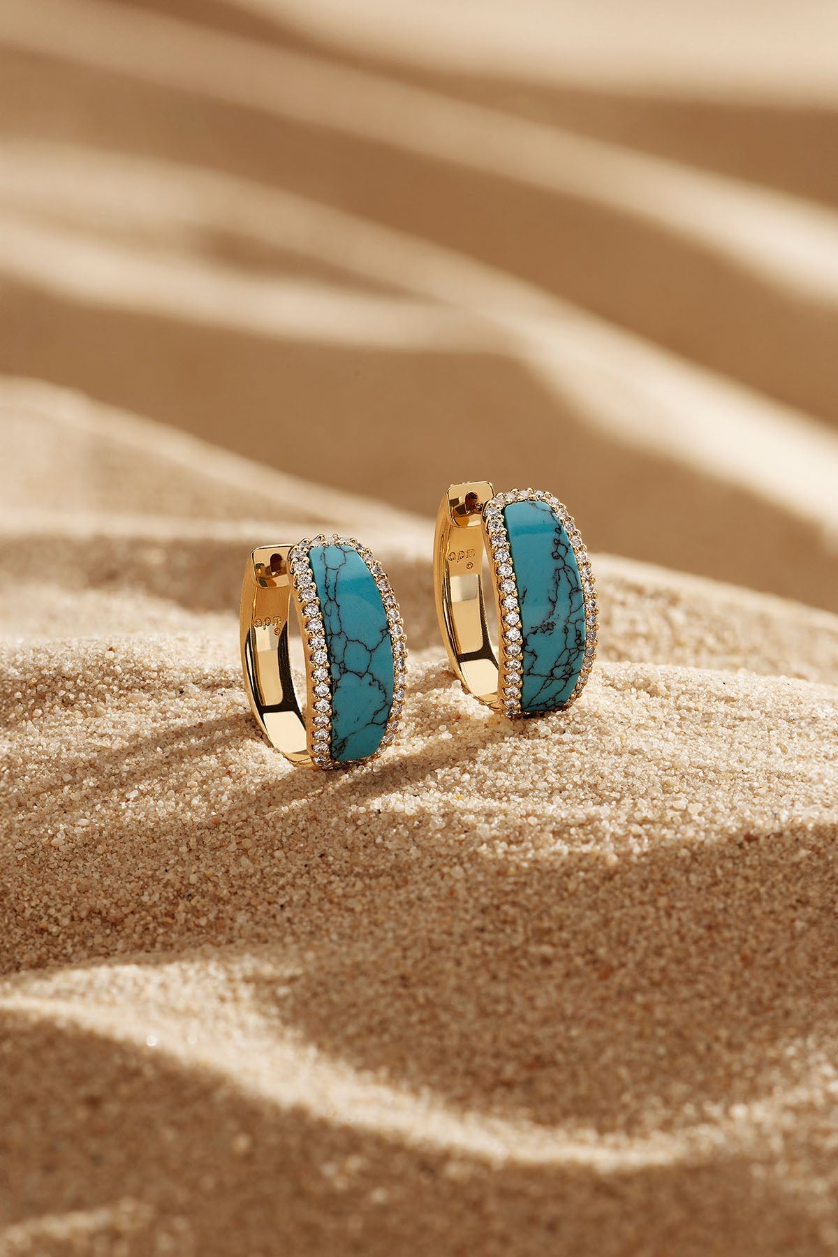 Earrings, APM Monaco. Yellow gold hoop earrings with lagoon blue accents and pavé diamond edging; two-hoop design and a clean, classic silhouette.
