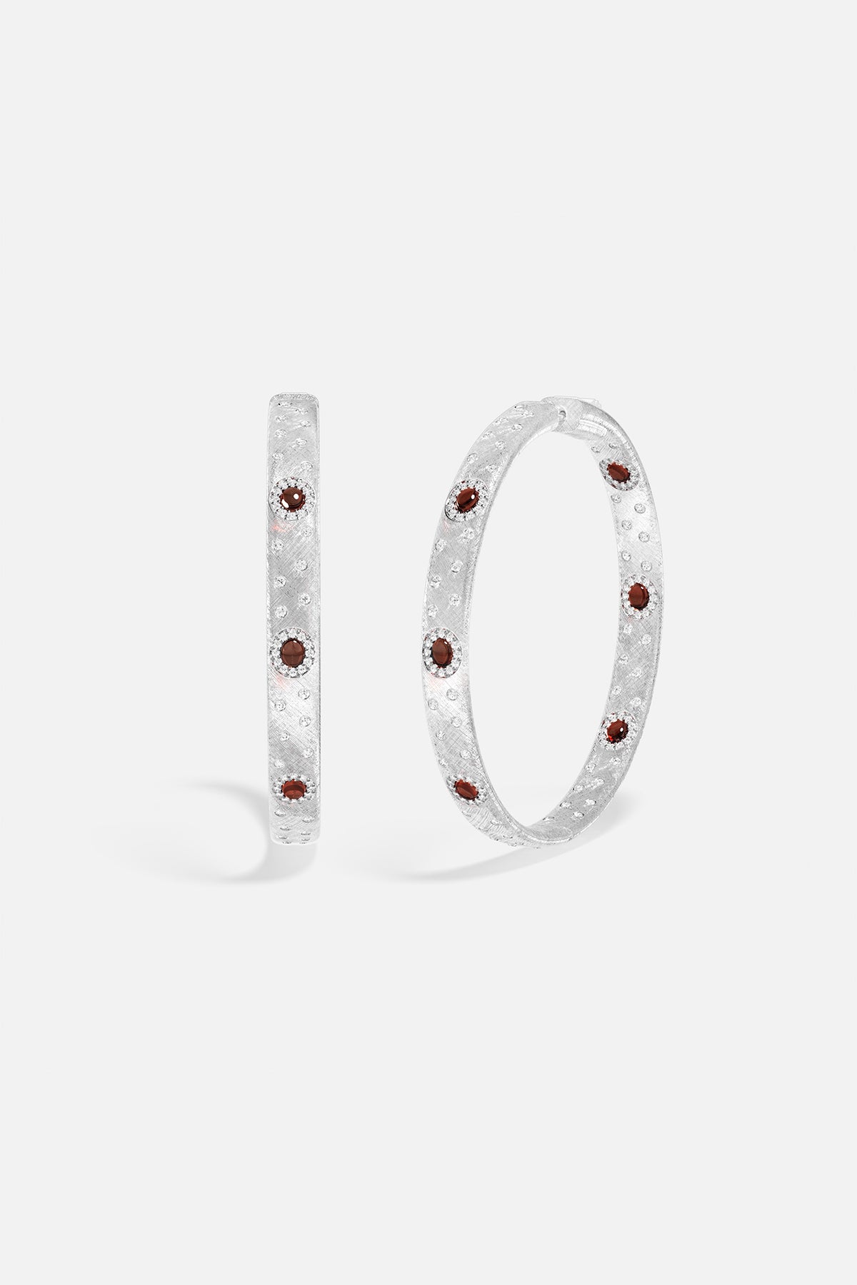APM Hoop Earrings, brushed rhodium finish glowing with deep red accents.