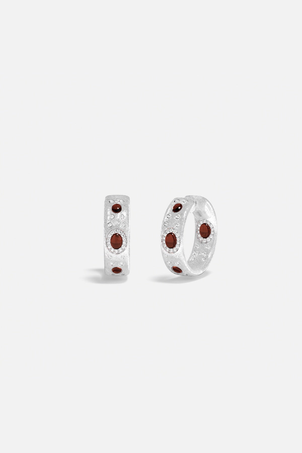 APM Hoop Earrings in rhodium finish, deep red accents glowing with quiet elegance.