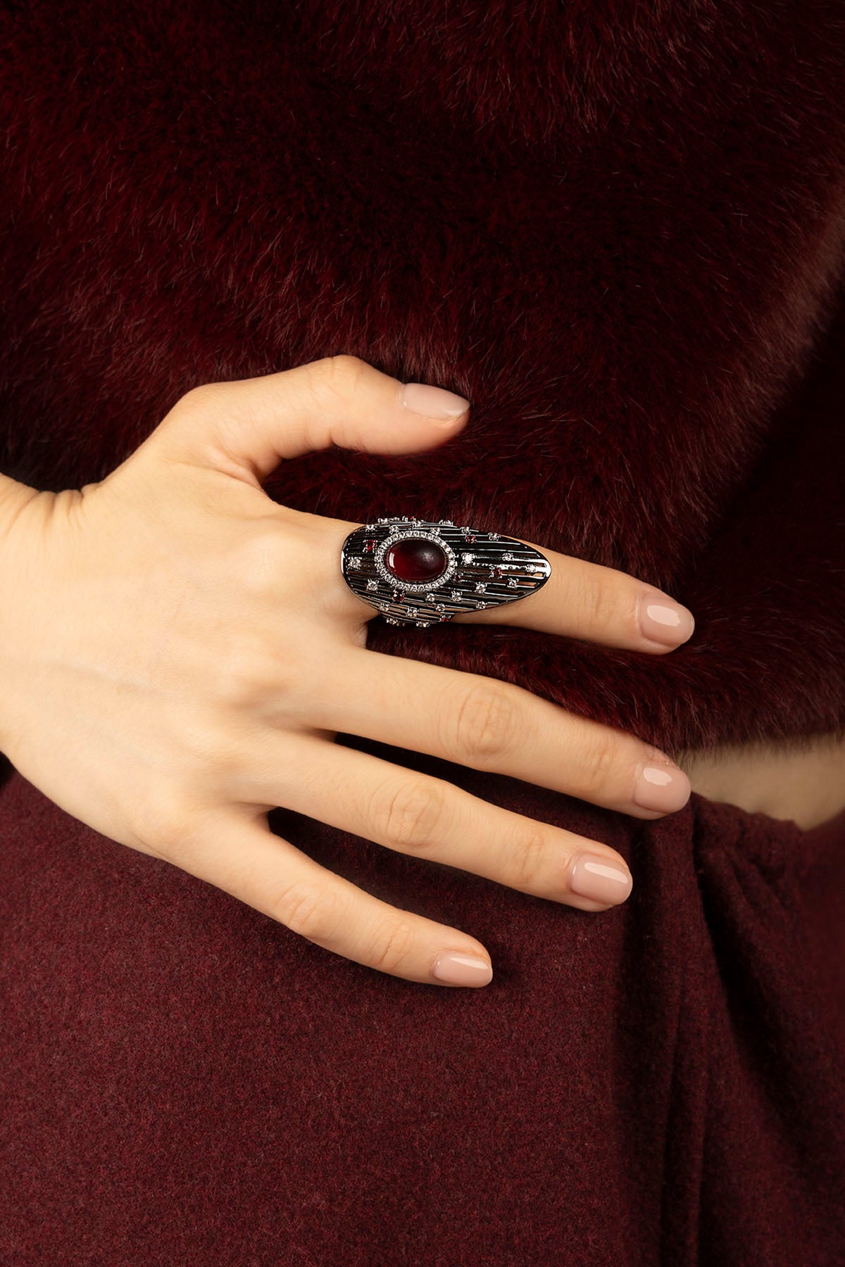Woman wearing APM Ring, a bold red gem framed in rhodium finish elegance.