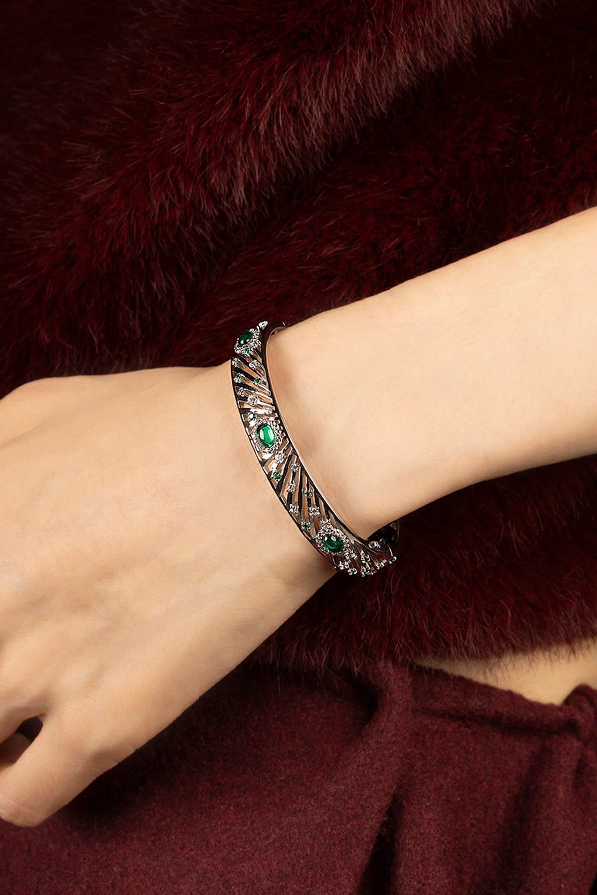 Woman wearing APM bangle, emerald sparkle meets rhodium finish, quiet winter allure.