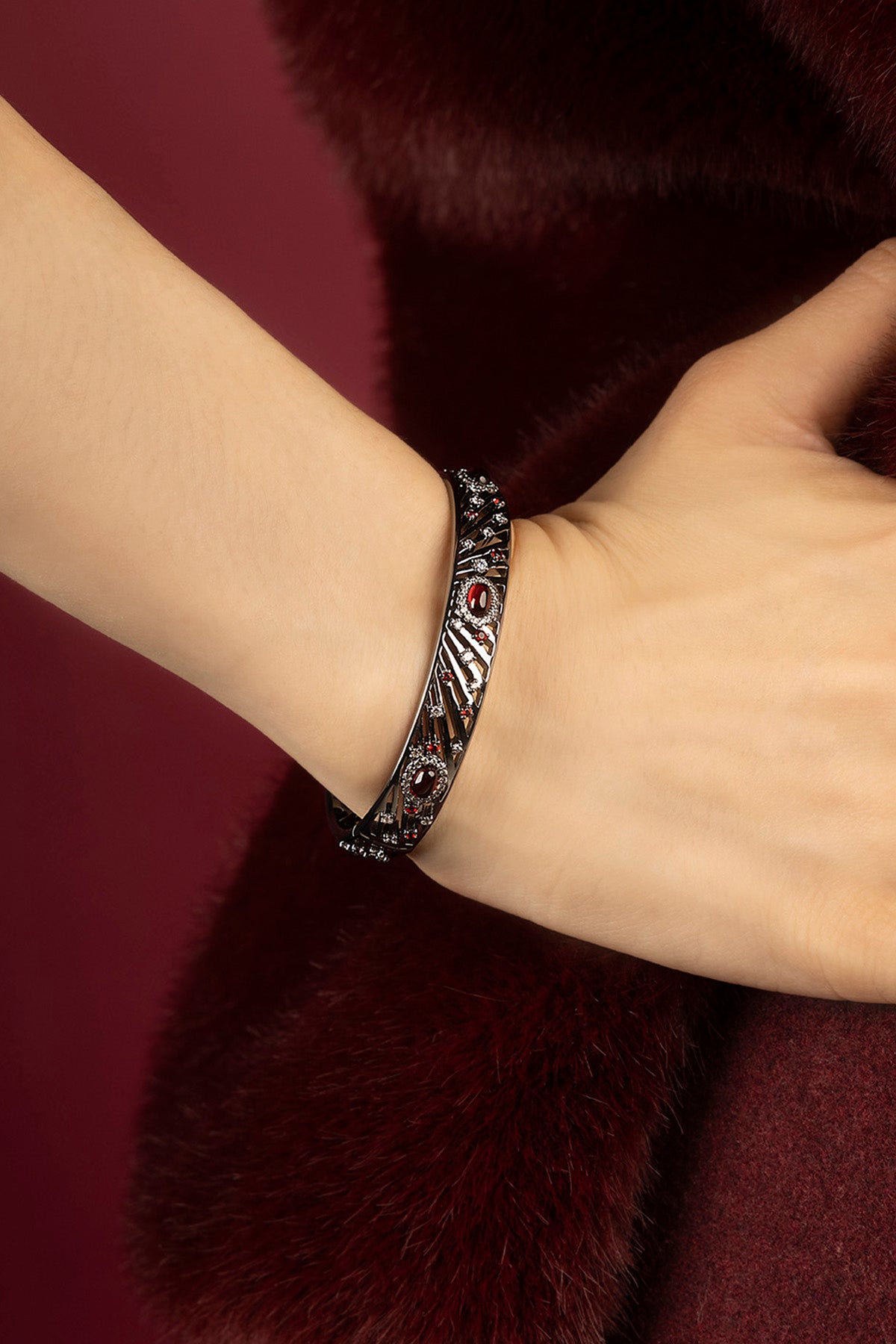 Woman wearing APM Monaco bangle, a bold statement of nocturnal elegance and crimson allure.