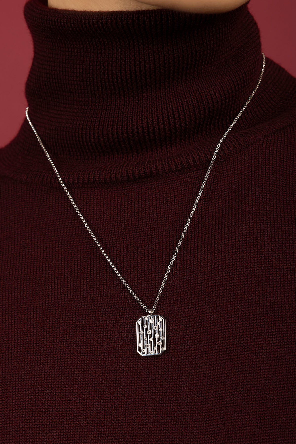 Man wearing APM Monaco pendant necklace, a quiet statement over burgundy knit.