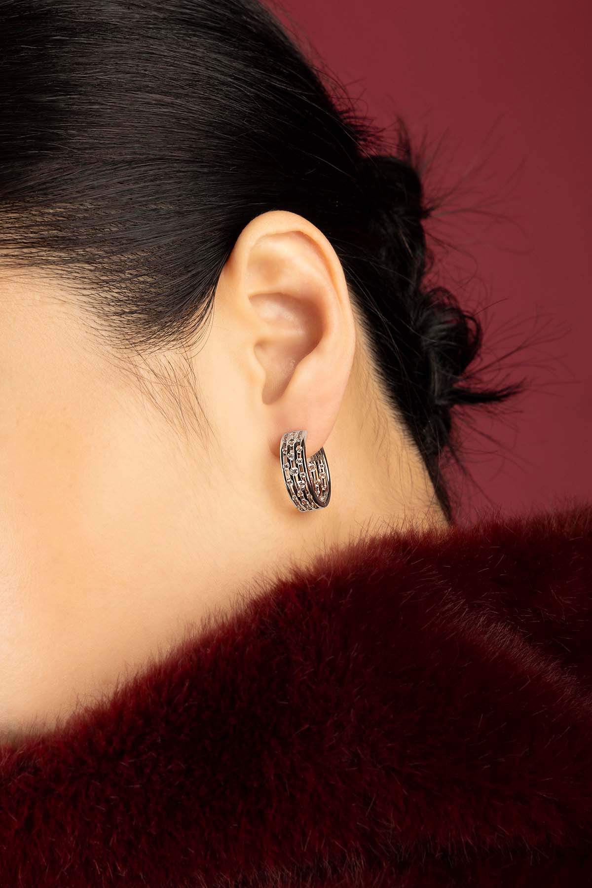 Woman wearing APM Monaco hoop earrings, a sparkling whisper of quiet elegance.