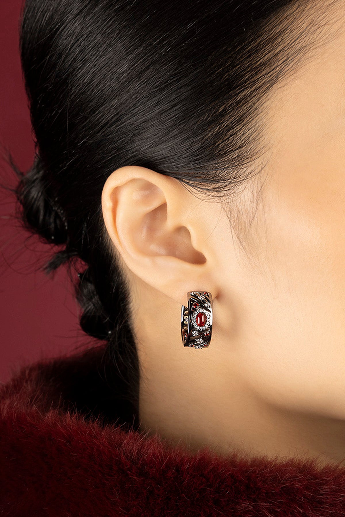 Woman wearing APM Hoop Earrings, a bold whisper of red and rhodium finish.