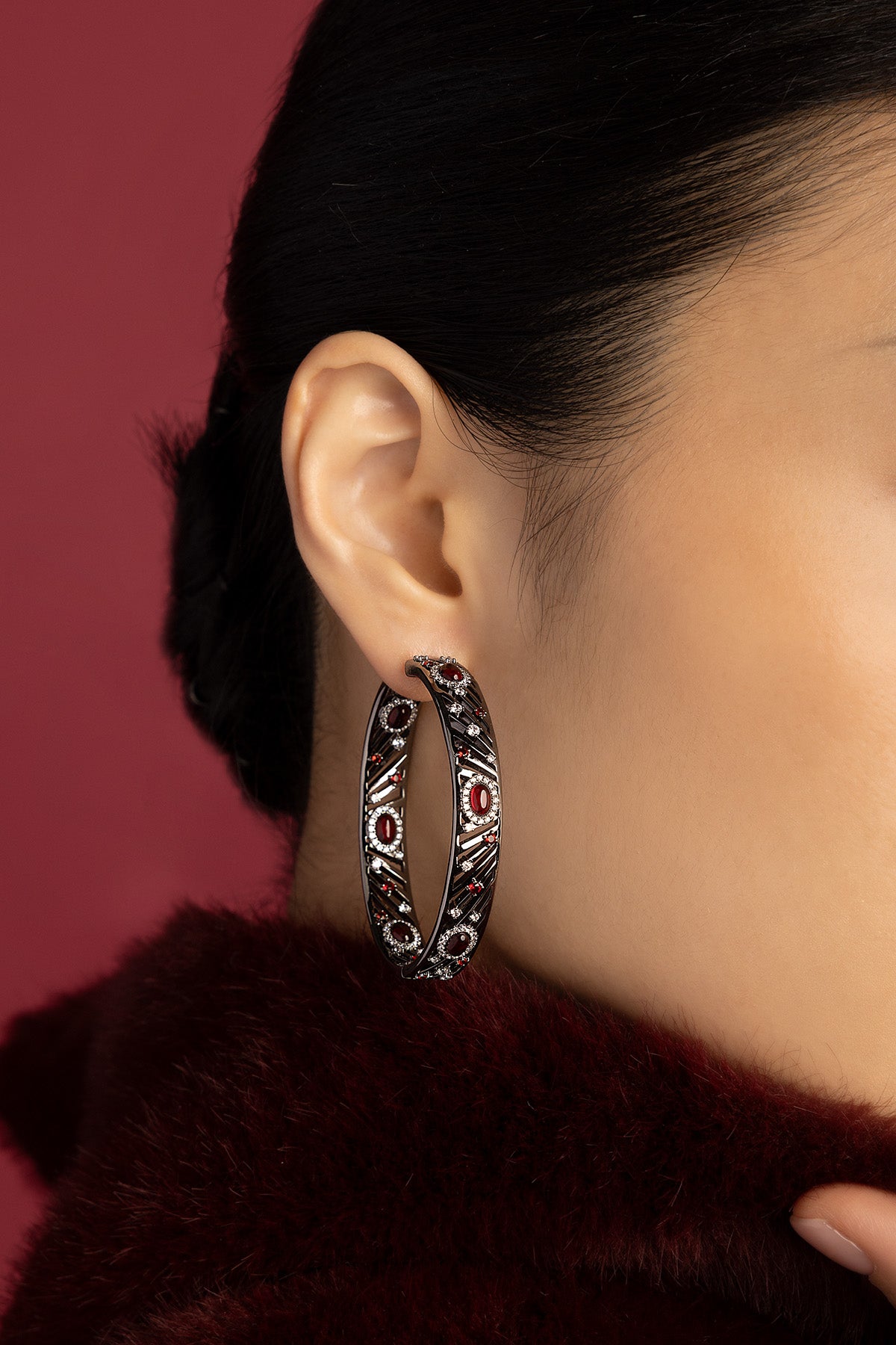 Woman wearing APM hoop earrings, bold noir allure with crimson sparkle.