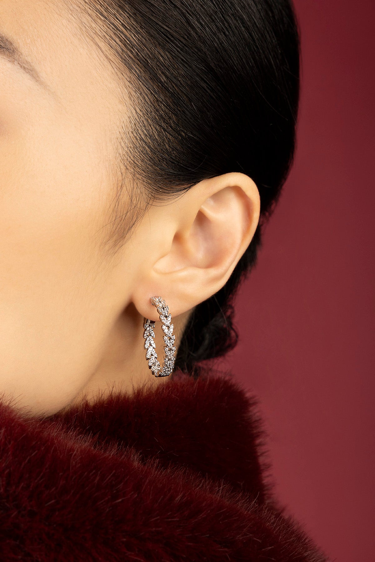 Woman wearing APM hoop earrings, a shimmering whisper of understated glamour.