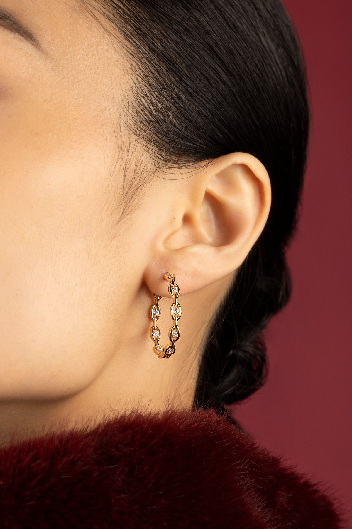 Woman wearing APM Monaco hoop earrings, a golden glow of quiet elegance.