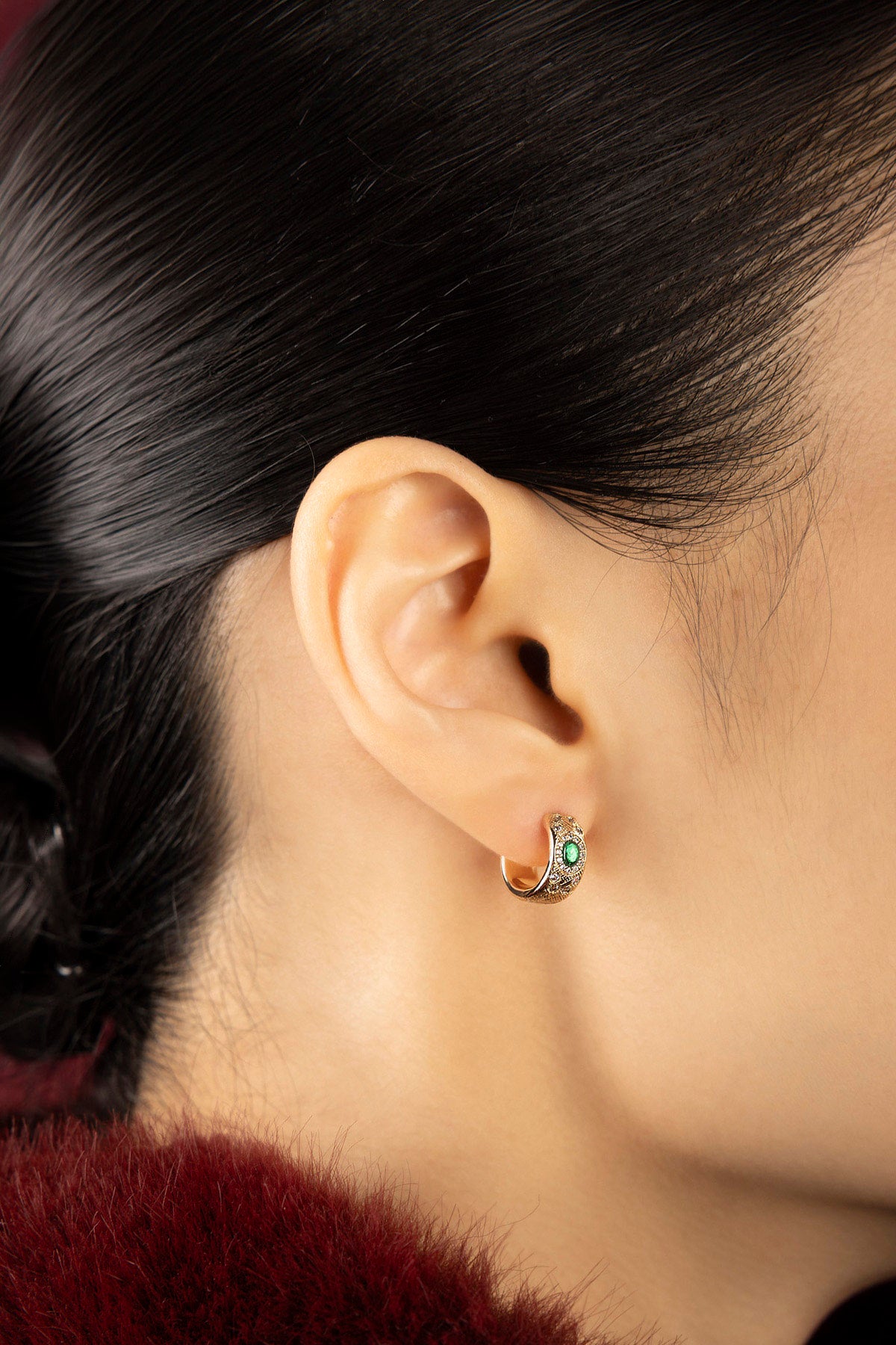 Woman wearing APM hoop earrings, a green spark of quiet elegance.