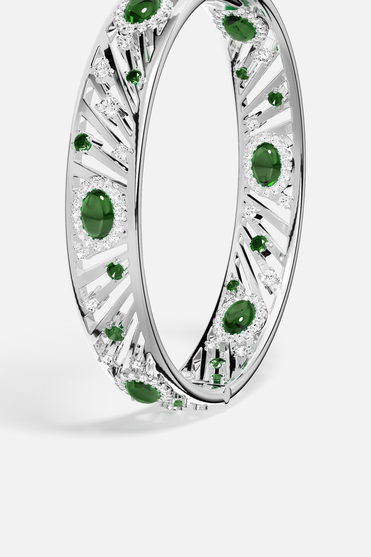 APM Monaco bangle in rhodium finish, radiant green stones glowing with quiet luxury.