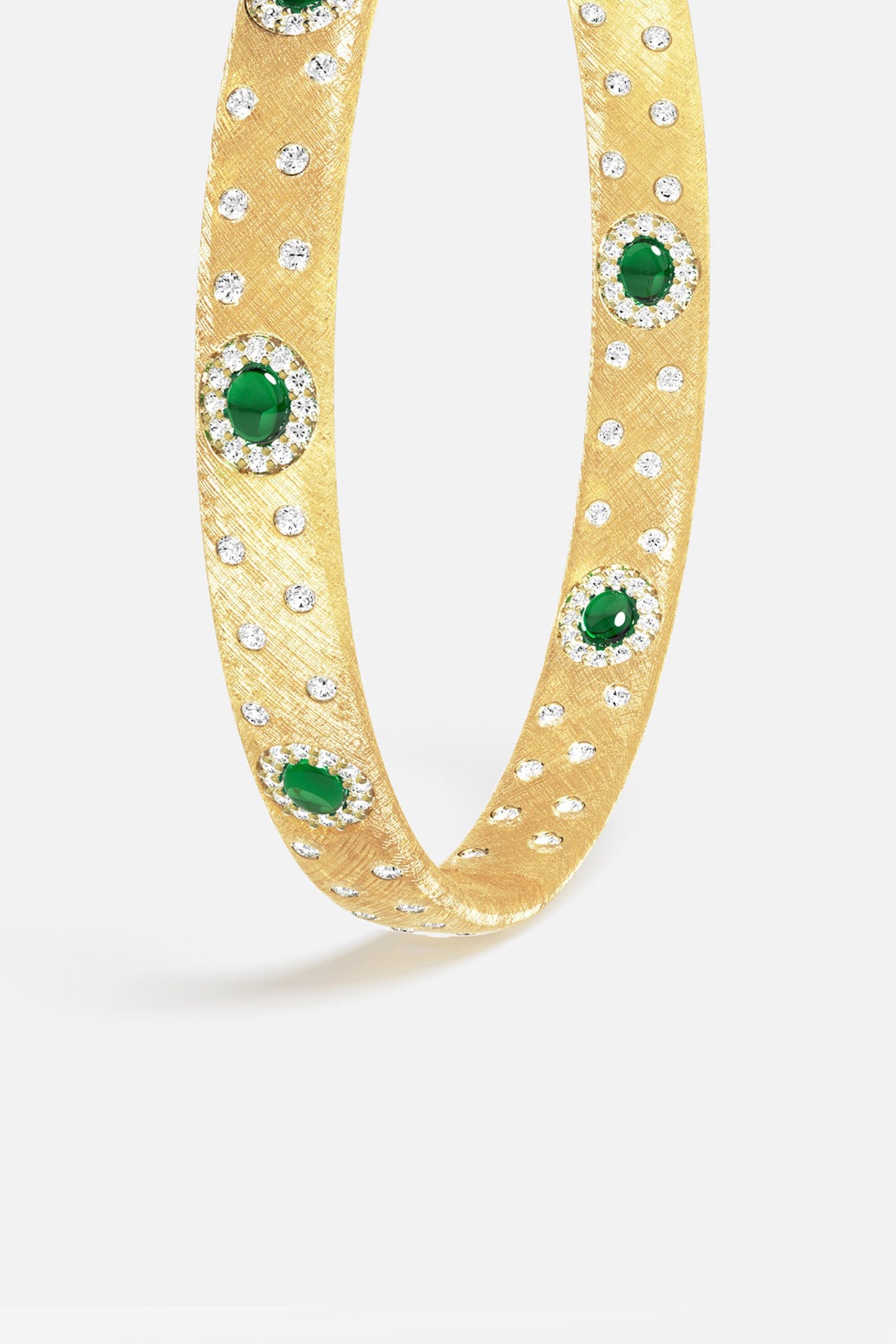 APM Bangle in golden brushed finish, scattered sparkle and emerald green cabochons, quiet opulence.