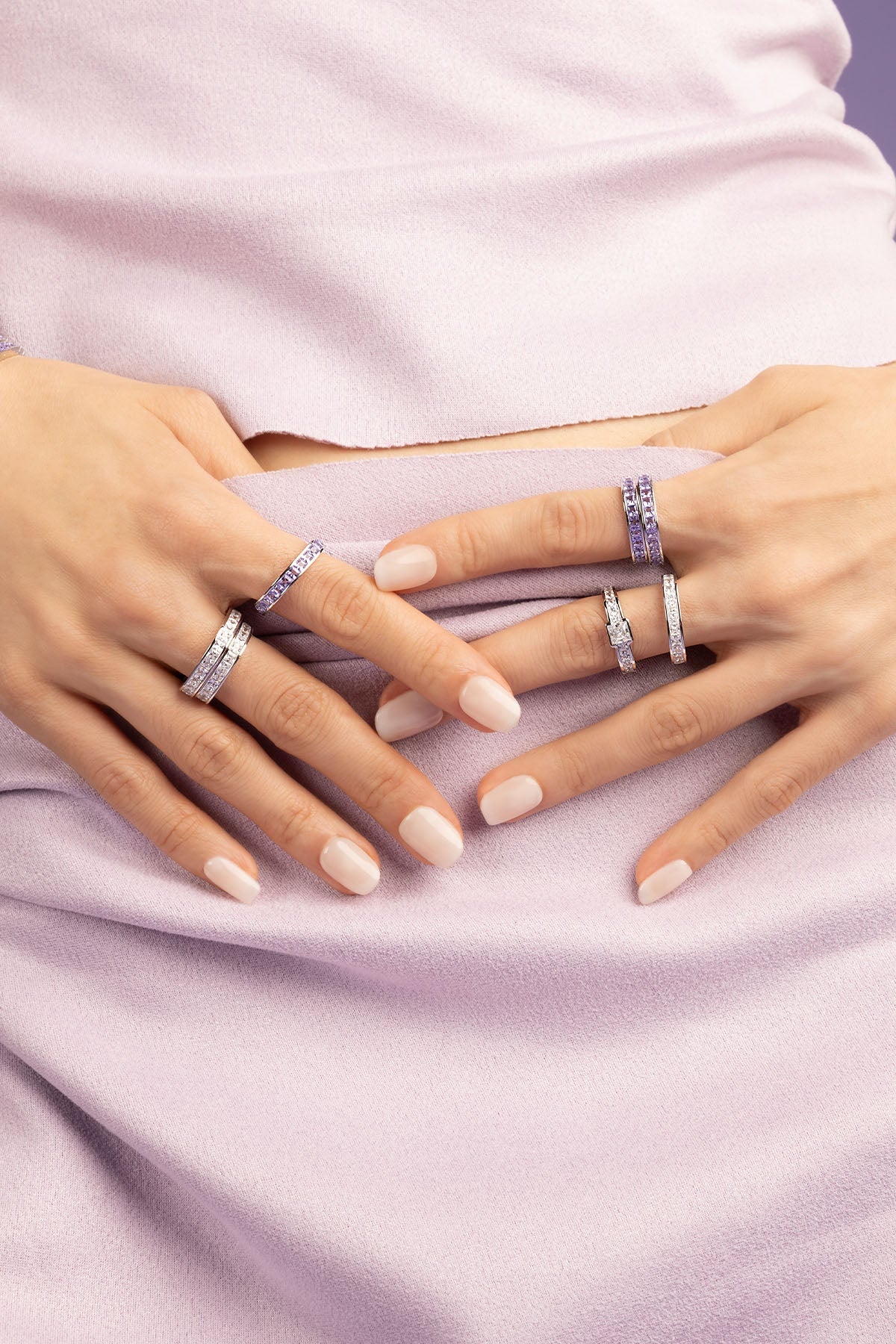 Hand wearing a white zirconia ring with a purple shirt