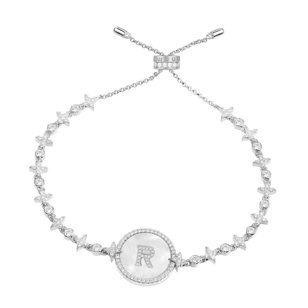 Bracelets APM Monaco. Silver chain bracelet with small white stars and circle motifs and a central circular pendant featuring a white background with the letter R.