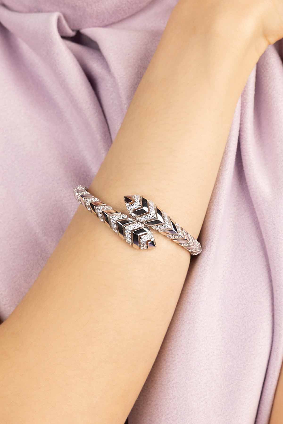 Silver bracelet on a person's wrist with a soft pink fabric background