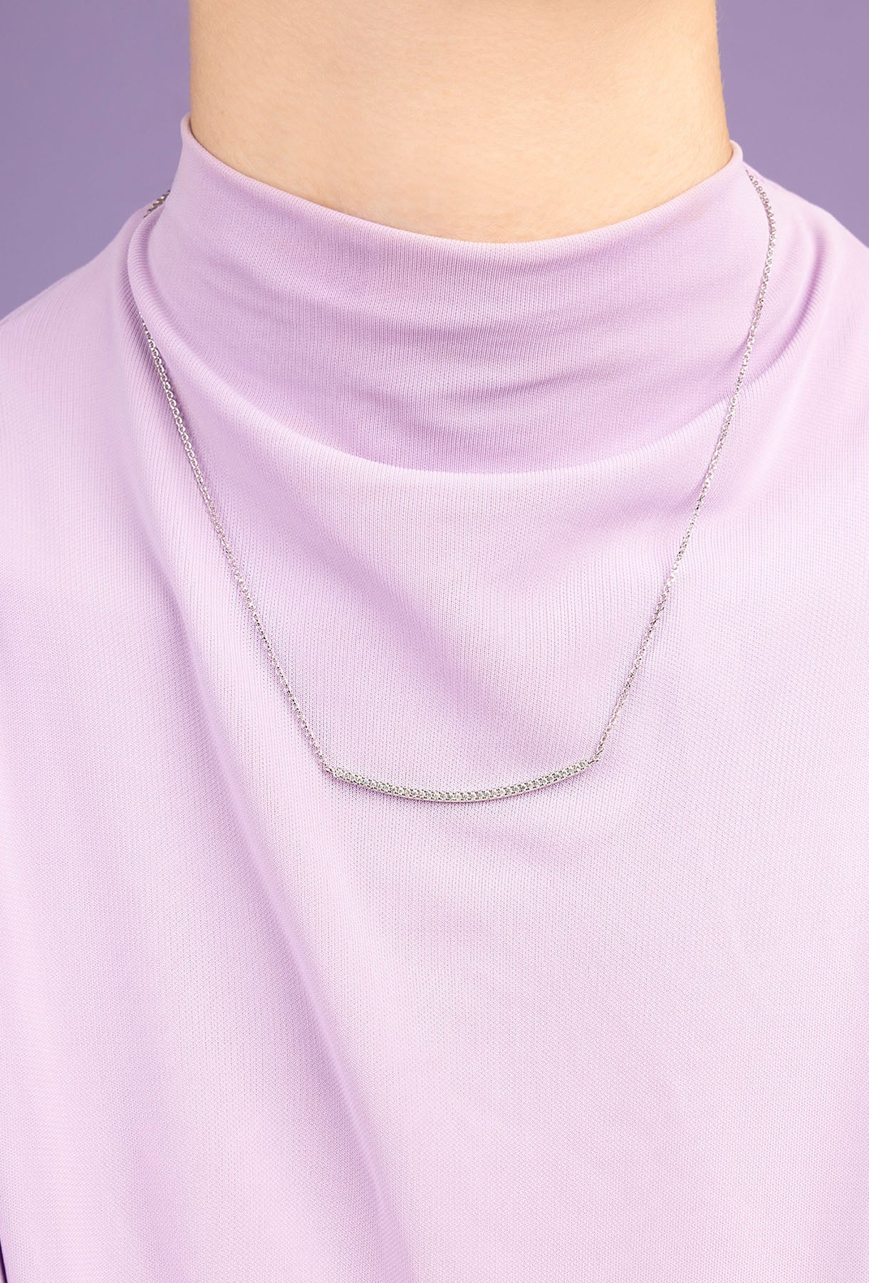 APM MONACO silver necklace on a model wearing a light purple top against a purple background