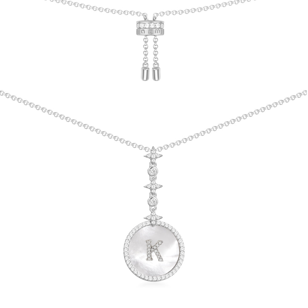 Necklaces APM Monaco: white-tone chain with a round pavé-diamond pendant featuring a centered letter K and a slider closure.