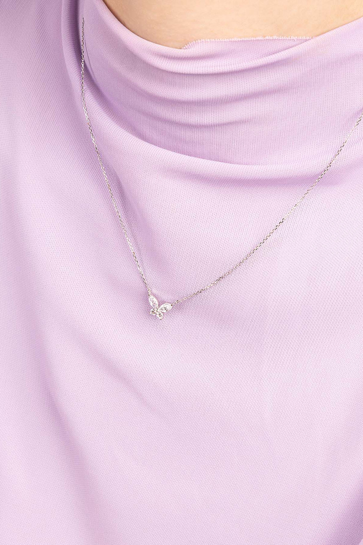 Necklace with a small pendant on a light purple top