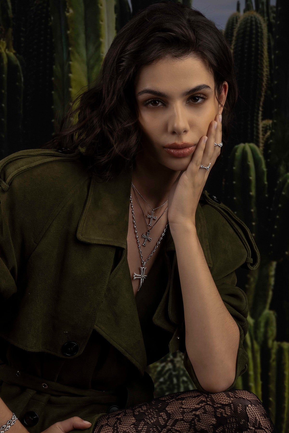 Woman in a green jacket and jewelry with cacti in the background