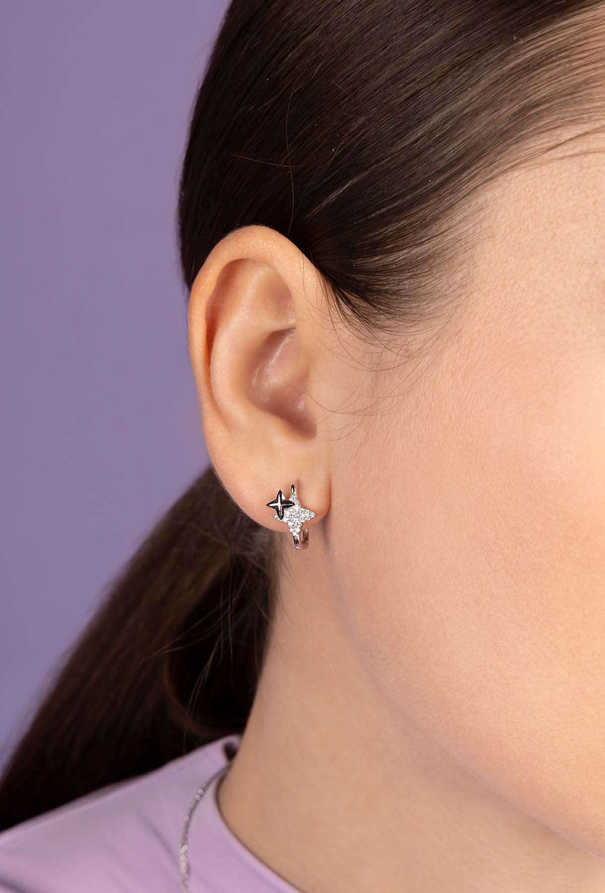 Close-up of an ear wearing APM MONACO star-shaped earring 