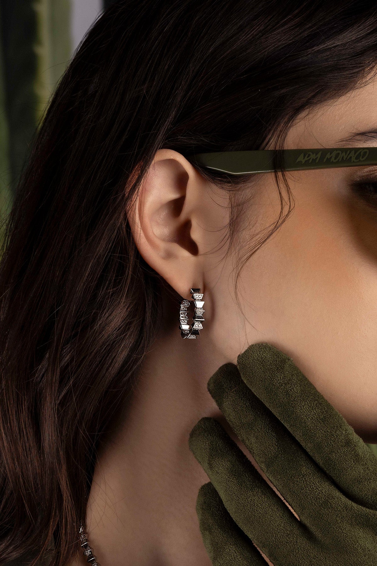 Close-up of an ear wearing a silver hoop earring with a blurred background