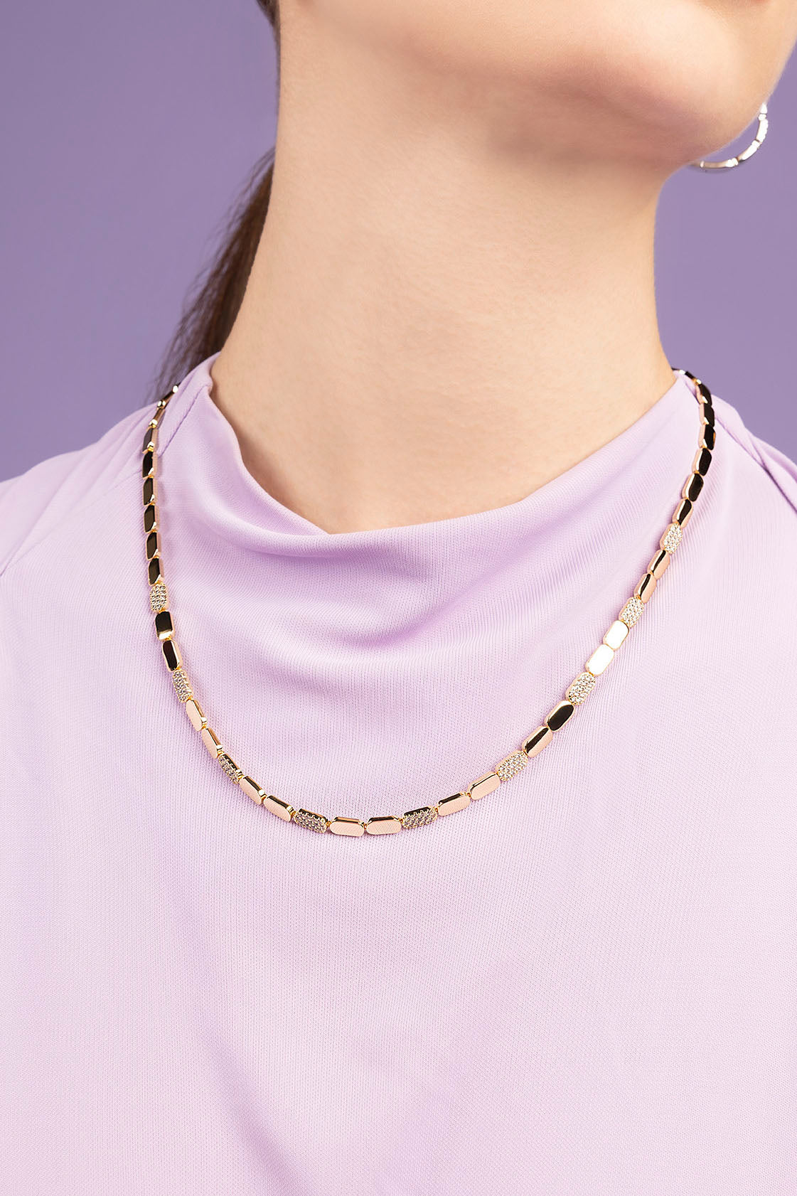 APM MONACO rose gold chain necklace worn by a person against a purple background