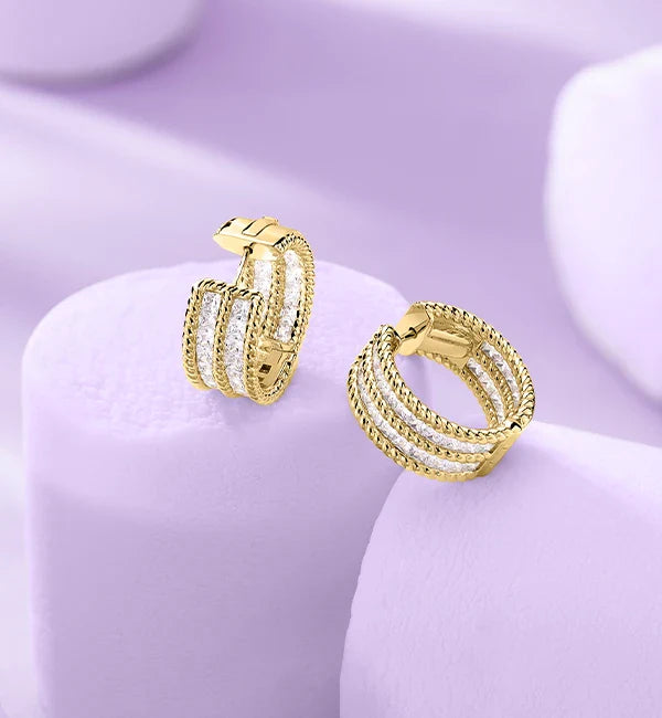 APM MONACO yellow gold torsade earrings on a light purple marshmallow
