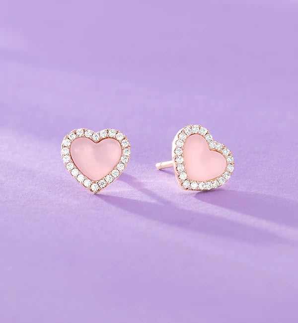 Close-up of a hand wearing APM MONACO rose gold ring with hoops on a blurred background