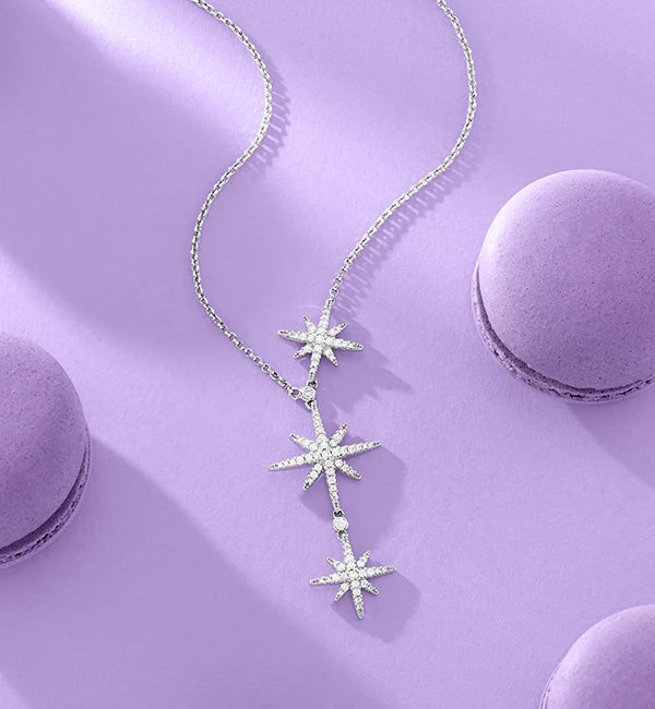 APM MONACO star-shaped necklace on a purple surface with macarons