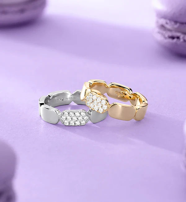 Two APM MONACO yellow gold and silver rings on a light purple background