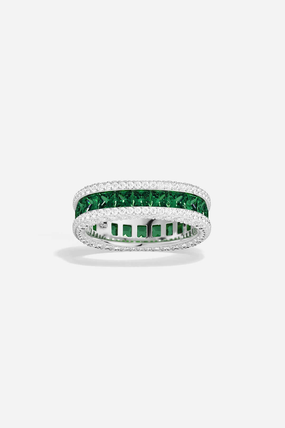 APM MONACO ring with green gemstones and white metal on a light gray background