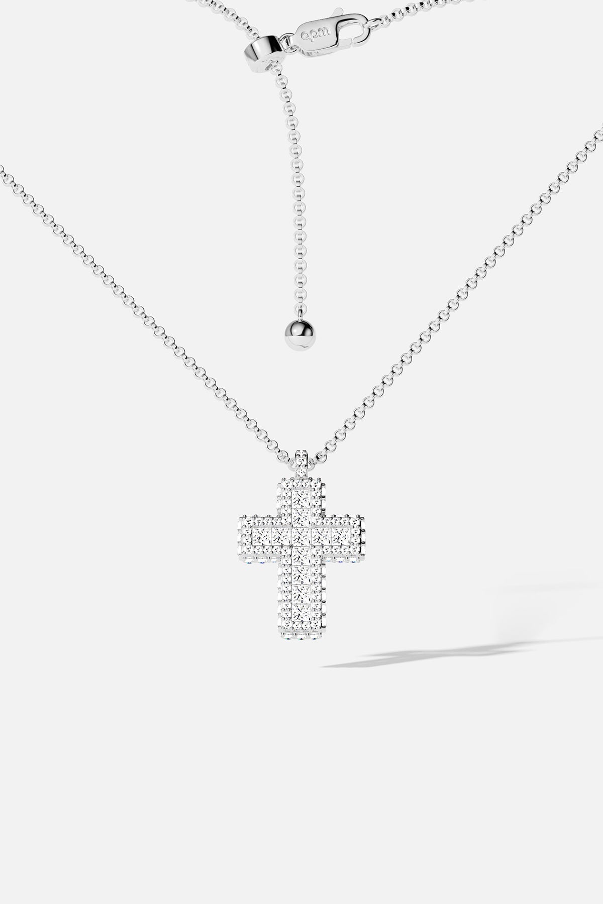 Silver tone cross necklace with white stones on a white background
