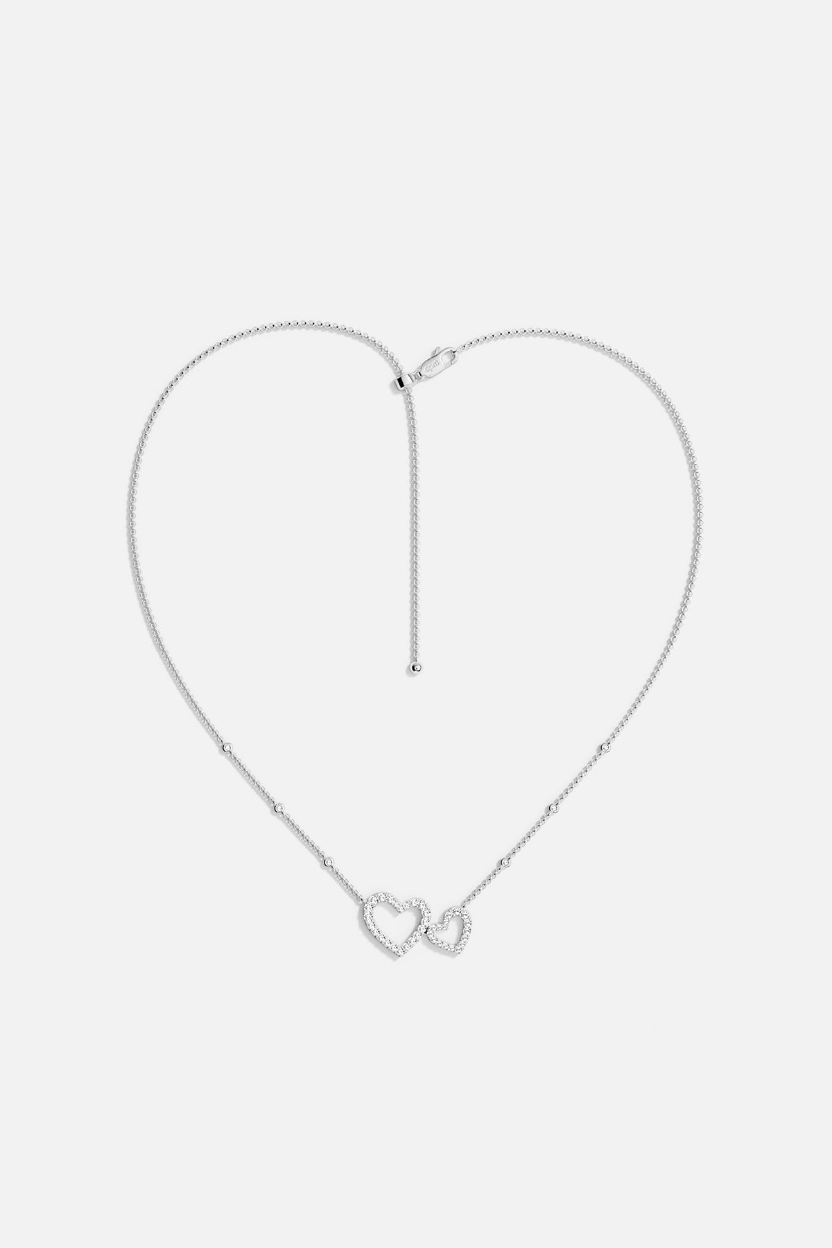 APM MONACO necklace in white with heart-shaped pendants on a light gray background