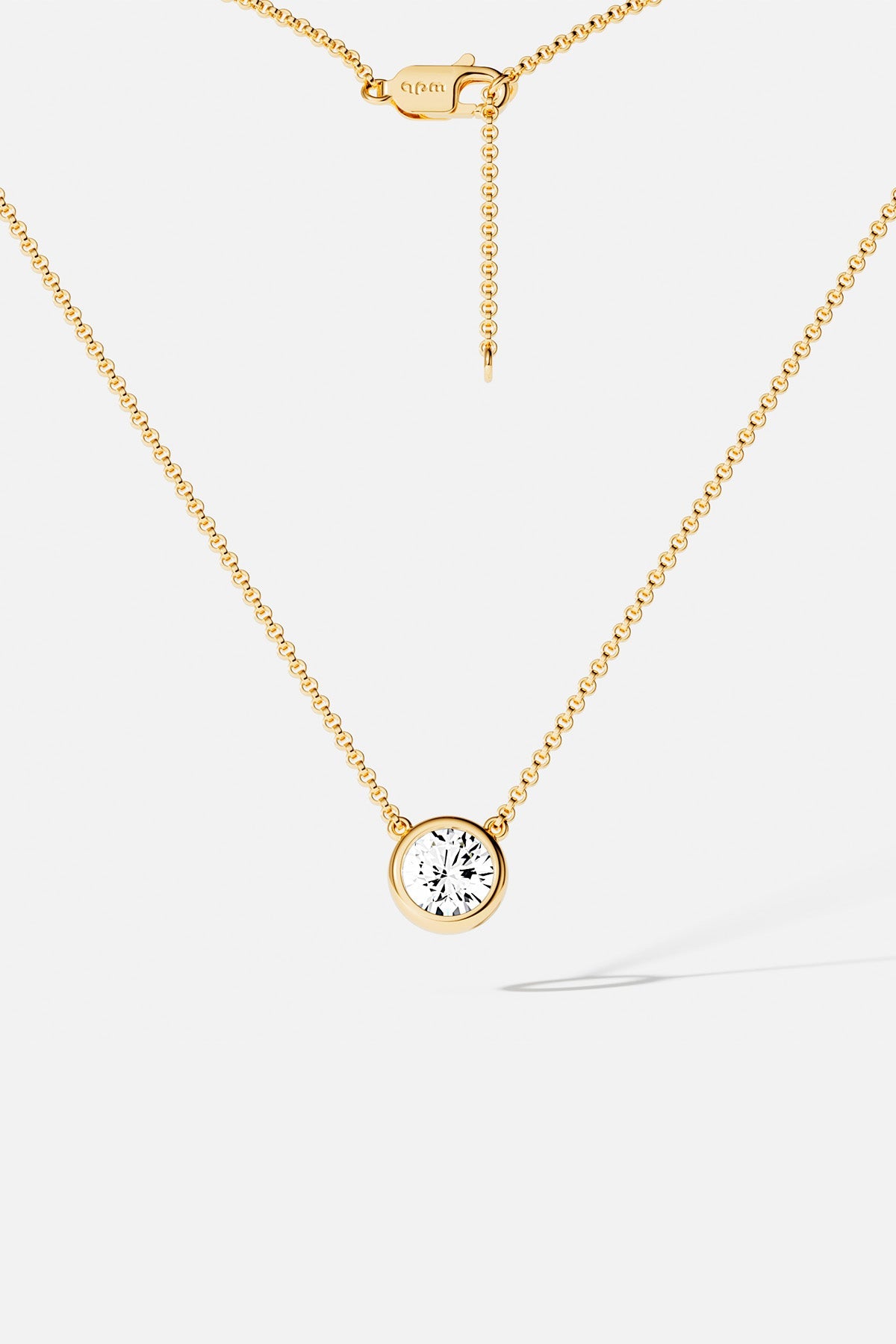 Necklaces APM Monaco, yellow gold chain with a single round clear gemstone pendant.