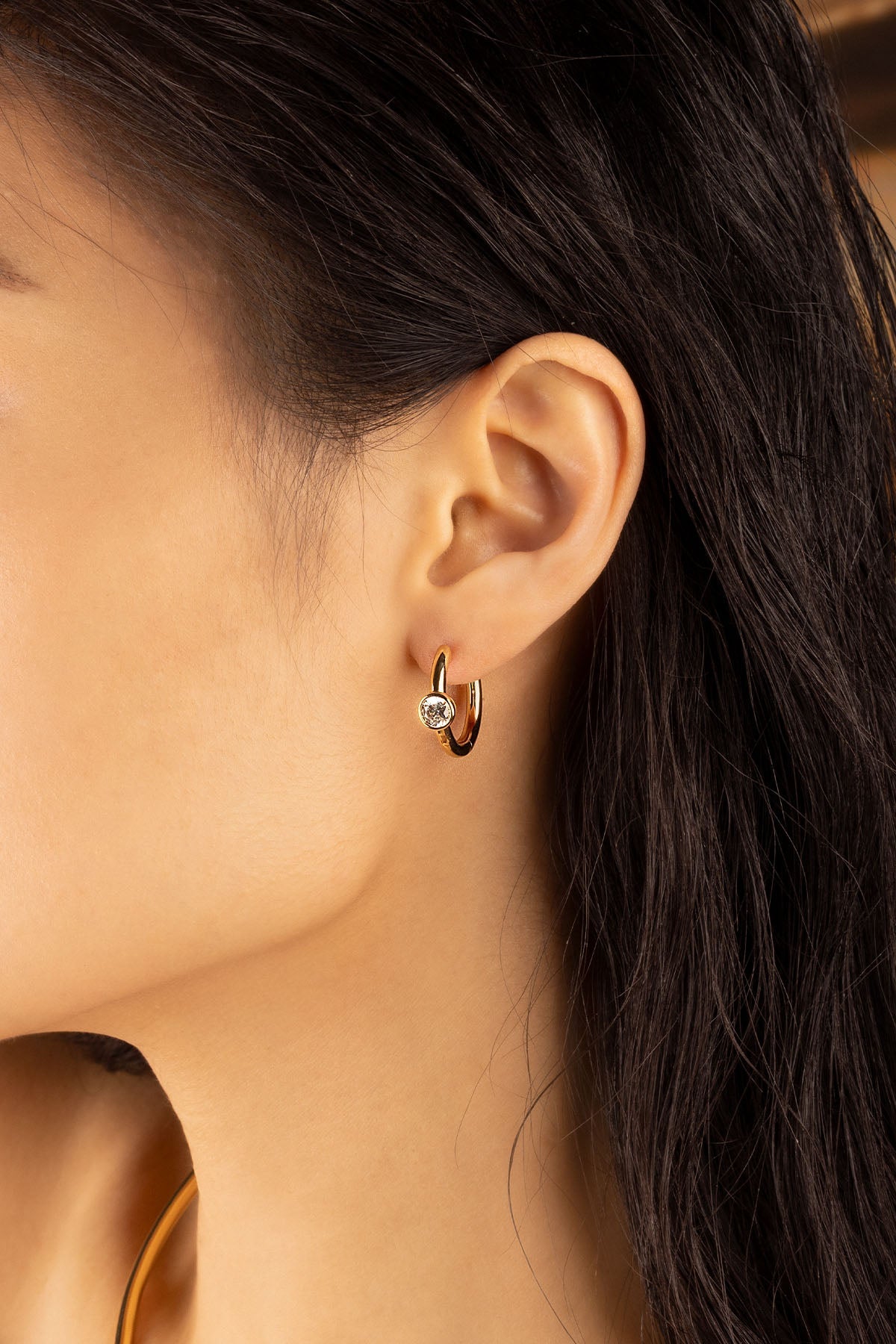 Earrings APM Monaco. Yellow gold small hoop with a clear stone.